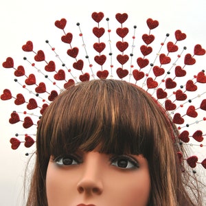 May include: A red glitter heart headband with a crown of hearts. The headband is made of wire and has a row of hearts around the top. The hearts are all red and have a glitter finish.