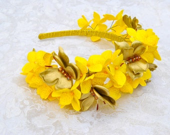 May include: A yellow headband with a floral design. The headband is decorated with yellow flowers and gold butterflies.