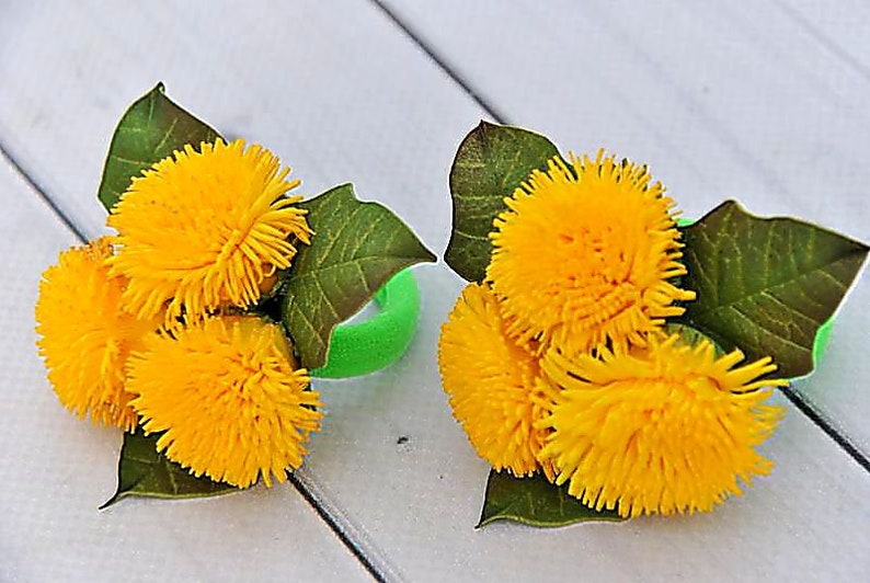 Puede incluir: Dos gomas para el pelo verdes decoradas con flores de diente de le&oacute;n amarillas y hojas verdes.