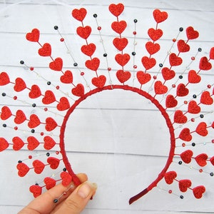May include: Red glitter heart headband with a wire frame and dangling beads. The headband is decorated with a row of red glitter hearts and has a row of dangling beads in silver, red, and black.
