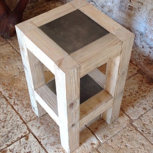 Może przedstawiać: Mały drewniany stolik pomocniczy z szarym blatem z płytek i dolną półką. Stolik wykonany jest z naturalnego drewna z jasnym wykończeniem.