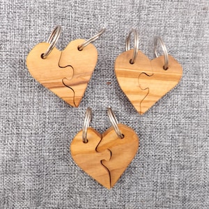 Herz-Puzzle 2 Schlüsselanhänger vereint in einem, um mit Ihren Liebsten zu teilen. Handgefertigte ineinandergreifende Herzstücke aus Olivenholz.