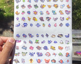 Op de afbeelding: Een vel met stickers met verschillende Pokémon-personages in een gepixelde stijl. De stickers zijn gerangschikt in rijen en kolommen op een witte achtergrond. De personages zijn kleurrijk en omvatten populaire Pokémon zoals Pikachu, Charmander, Bulbasaur en Squirtle.