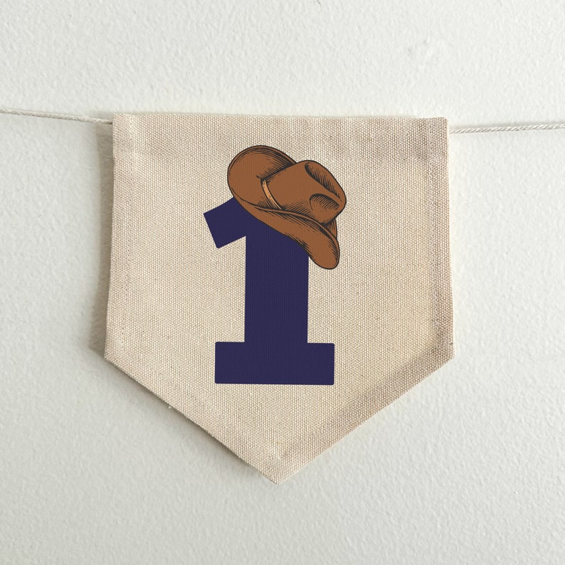 May include: A beige fabric pennant with a navy blue number "1" and a brown cowboy hat on top.