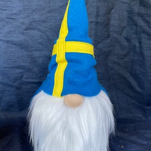 May include: A blue gnome with a white beard and a blue and yellow hat. The hat has a yellow stripe that resembles the Swedish flag.