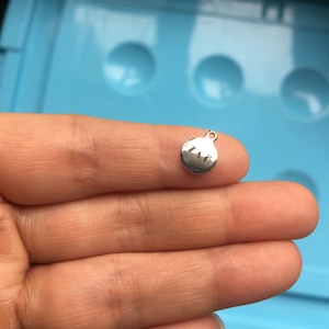 May include: A silver charm with the letters "LNO" engraved on it.