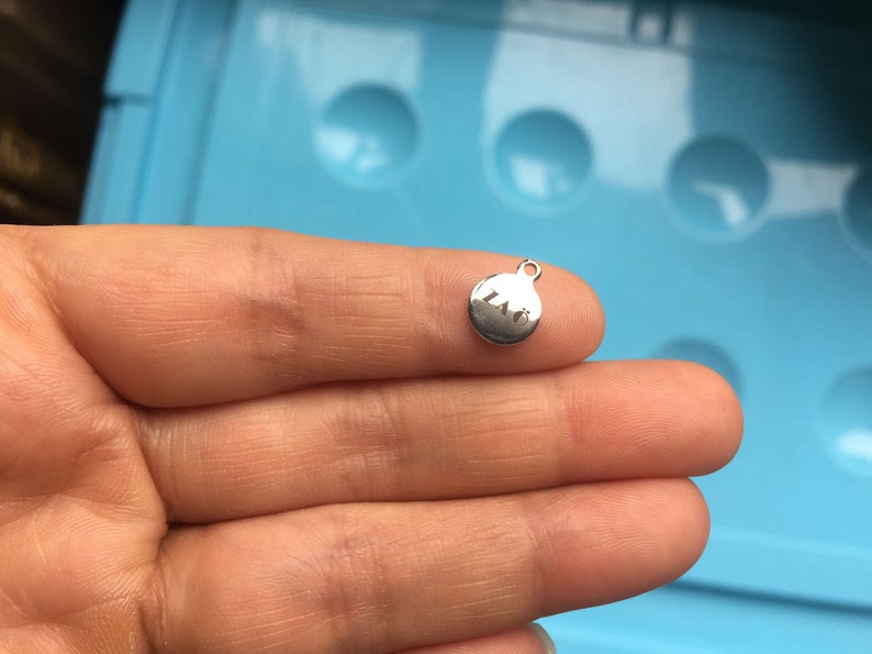 May include: A silver charm with the letters "LNO" engraved on it.