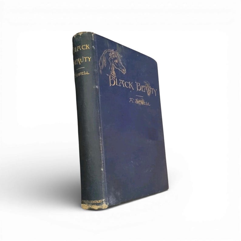 May include: A vintage hardcover book titled "Black Beauty" by Anna Sewell. The book has a dark blue cover with gold lettering and a horse illustration. The spine is a darker shade of blue.