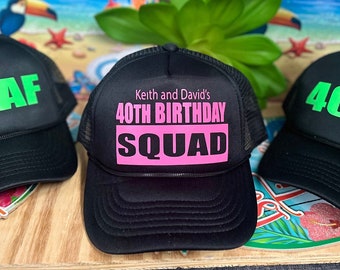 Puede incluir: Gorras de camionero negras con la parte trasera de malla y el texto "40 AF" en verde brillante. Una gorra tiene el texto "Keith and David's 40TH BIRTHDAY SQUAD" en rosa. Las gorras están sobre una superficie de madera.