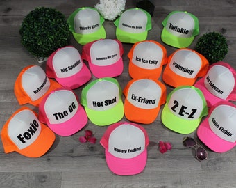 Puede incluir: Una colección de 15 gorras de camionero de neón con diferentes frases impresas en la parte delantera. Las gorras son de color rosa, naranja y verde. Las frases incluyen "Thirsty Kirsti", "Twinkle", "Jamaica Me Crazy", "Ice Ice Lolly", "#winning", "Big Spender", "Outnumber", "Ex-Friend", "Hot Shot", "2 E-Z", "The OG", "Gone Fishin', "Foxie" y "Happy Ending".