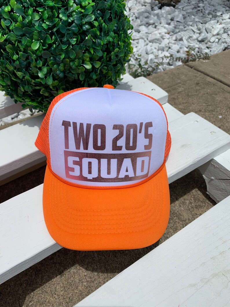 May include: Orange and white trucker hat with the text "TWO 20'S SQUAD" in brown letters.