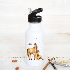 Op de afbeelding: Een witte waterfles van roestvrij staal met een zwarte dop en een rietje. De fles heeft een afbeelding van een bruin paard en veulen en de naam "Ida" erop gedrukt.