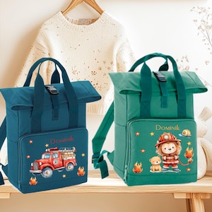 Può includere: Due zaini per bambini, uno blu e uno verde, con una patta ribaltabile. Lo zaino blu ha un design di camion dei pompieri rosso e lo zaino verde ha un design di leone e orso. Entrambi gli zaini hanno il nome Dominik ricamato.