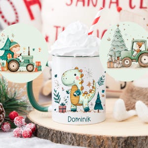 Könnte beinhalten: Weißer Keramikbecher mit grünem Henkel, mit einem Cartoon-Dinosaurier und dem Namen "Dominik". Der Becher hat eine Schlagsahne-Topping und einen rot-weiß gestreiften Strohhalm. Zwei runde Illustrationen eines Traktors mit einem Weihnachtsbaum befinden sich auf dem Becher.