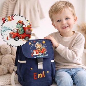 Può includere: Uno zaino blu navy a tema pompiere. La patta presenta un orso in un design di camion dei pompieri con stelle. Il nome "Emil" è stampato in arancione. Una grafica circolare mostra un dinosauro in un camion dei pompieri. Lo zaino ha cinghie bianche e una fibbia nera.