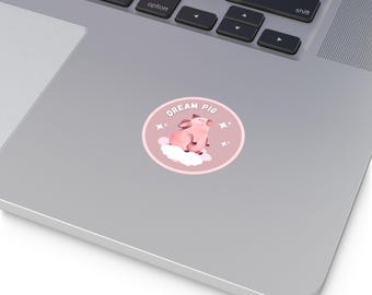 May include: A circular sticker with a pink pig on a cloud, and the words "DREAM PIG". The design is set against a light pink background, with star details. A cute, whimsical design.