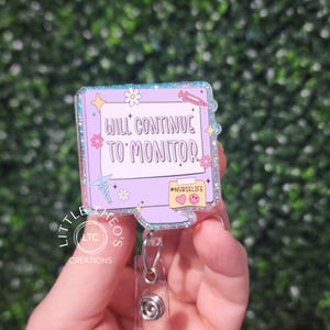 May include: A light purple badge reel with a computer monitor design. The monitor has the text "WILL CONTINUE TO MONITOR" and the hashtag "#NURSELIFE". The badge reel has a clear plastic retractable cord and a metal clip.