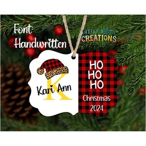 Puede incluir: Adorno navide&ntilde;o personalizado con borde festoneado blanco. El lado izquierdo presenta un dise&ntilde;o de gorro de Pap&aacute; Noel sobre una letra "K" amarilla y el nombre "Kari Ann". El lado derecho tiene un patr&oacute;n de cuadros de b&uacute;falo rojo y negro con "HO HO HO" y "Christmas 2024."