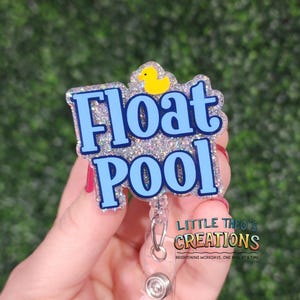 Peut inclure: Un porte-badge avec les mots "Float Pool" en bleu clair, soulignés de bleu plus foncé. Le badge a un fond scintillant et un canard en caoutchouc jaune. Le texte "Little Theo's Creations" est également visible.