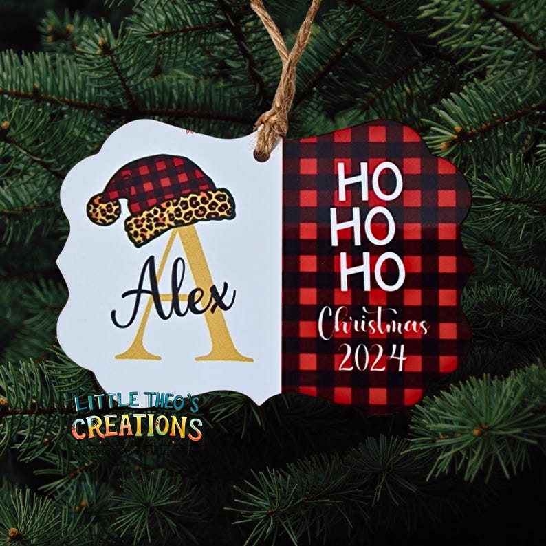 Puede incluir: Adorno navide&ntilde;o personalizado con borde festoneado blanco. El lado izquierdo presenta un dise&ntilde;o de gorro de Pap&aacute; Noel con borde de estampado de leopardo y el nombre "Alex" con una inicial dorada. El lado derecho tiene un patr&oacute;n de cuadros rojos y negros con "HO HO HO Christmas 2024".