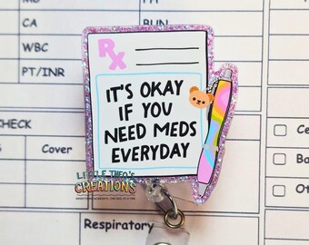 May include: A glittery badge reel with a prescription pad design. The text reads "IT'S OKAY IF YOU NEED MEDS EVERYDAY." A colorful pen and a small bear are also featured. The reel is attached to a clear plastic clip.