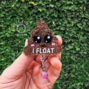 May include: A gold glitter poop emoji with a pink blush and the text "I FLOAT" on a clear retractable badge holder with a pink glitter charm.