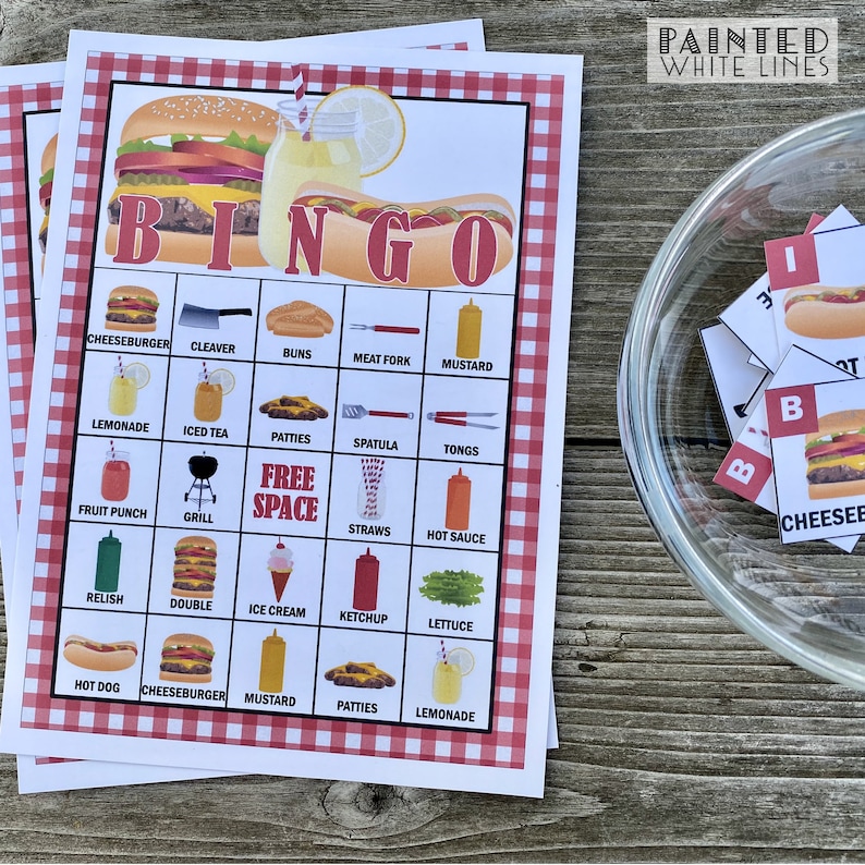 May include: A red and white checkered bingo card with a hamburger and hot dog design. The card has a free space in the middle and is filled with various food and grilling related items. The card is on a wooden table with a glass bowl of bingo chips.