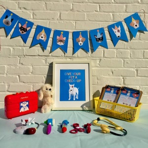 May include: A blue and white banner with cartoon dogs wearing party hats. The banner reads "Give your pet a check-up". There is a toy doctor's kit, a stuffed dog, and a yellow basket with paper forms.