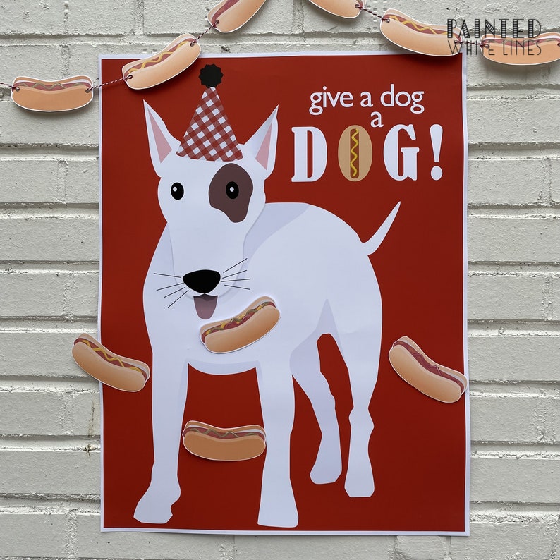 May include: A red and white printable game board with a white bull terrier wearing a red and white checkered party hat. The dog is looking up with its mouth open and has a hot dog in its mouth. The text on the board reads "give a dog a DOG!" and "painted white lines".