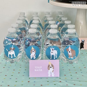 May include: A table with a light blue tablecloth with white polka dots. There are 15 clear plastic water bottles with blue and white dog stickers on them. The stickers feature dogs wearing party hats. A sign on the table reads "Toilet Water".