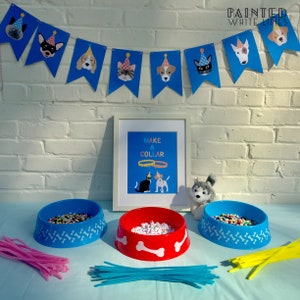 May include: A blue and white dog-themed party table setting with three dog bowls filled with colourful beads, pink and blue pipe cleaners, and a sign that says "Make a Collar".