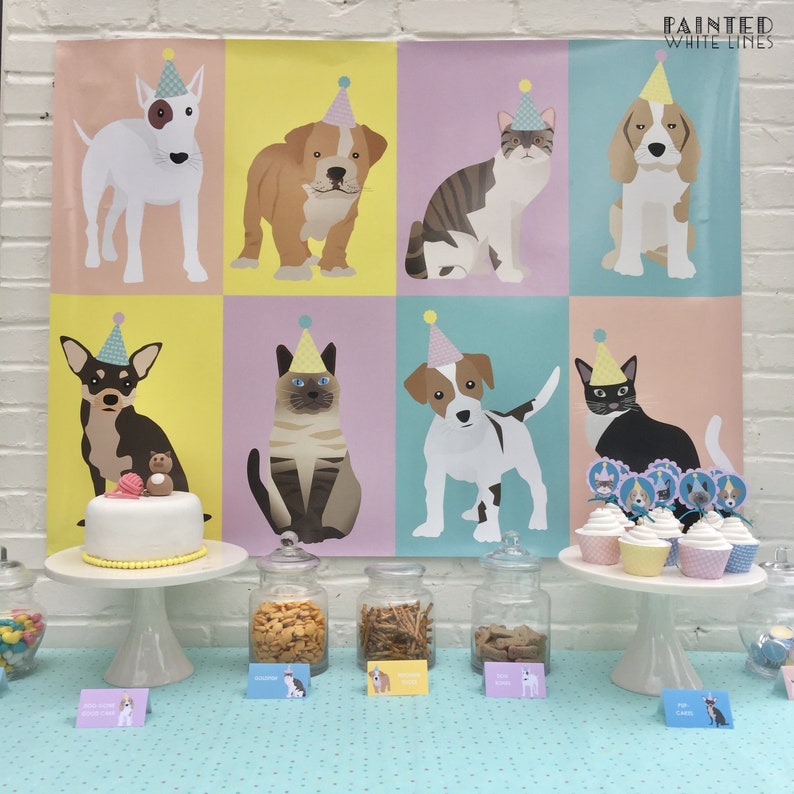 May include: A birthday party table setting with a cake decorated with a dog and cat figurine, cupcakes with animal toppers, and jars of snacks. A colorful backdrop features illustrations of dogs and cats wearing party hats. The backdrop has the text "Painted White Lines".