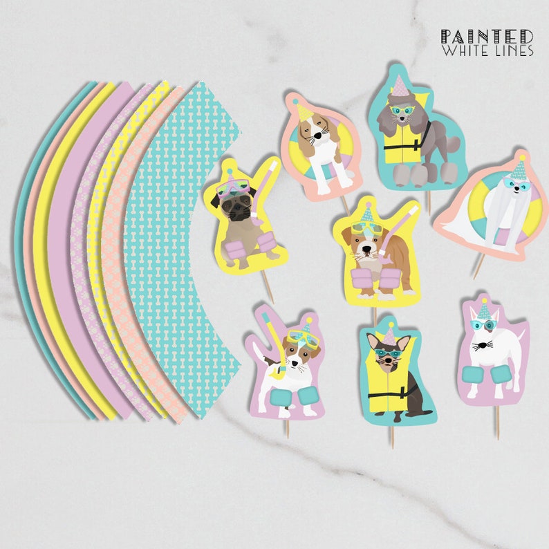 Puede incluir: Conjunto de adornos para cupcakes con diferentes razas de perros que llevan gafas de nataci&oacute;n y chalecos salvavidas. Los adornos est&aacute;n impresos en cartulina y tienen un dise&ntilde;o de l&iacute;neas blancas pintadas. El texto "PAINTED WHITE LINES" est&aacute; impreso en la parte superior de la imagen.