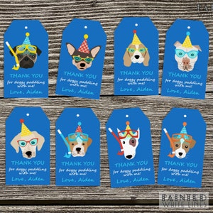 May include: Eight blue and white thank you gift tags featuring various cartoon dogs wearing goggles and party hats. The text on the tags reads "Thank you for doggy paddling with me! Love, Aiden".