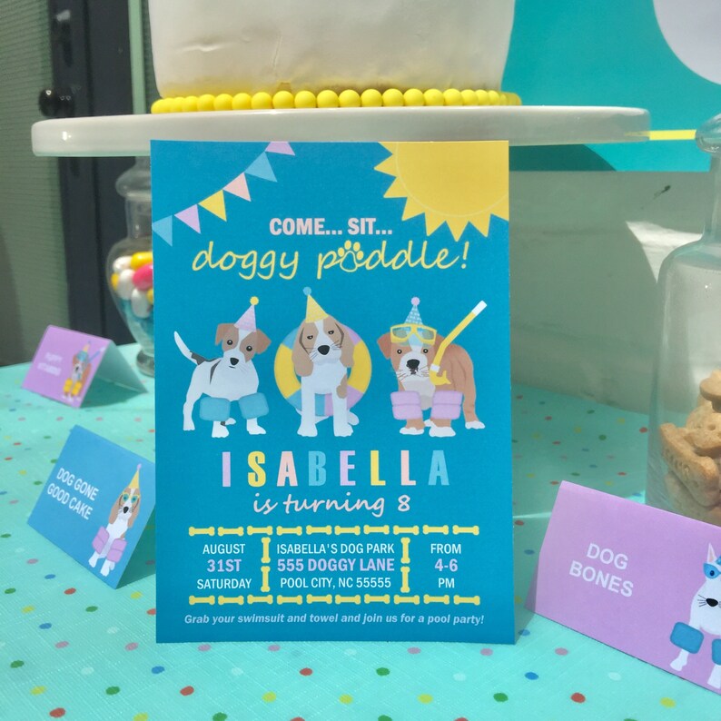 May include: A blue and yellow birthday party invitation with a cartoon dog wearing a party hat and swimming goggles. The invitation says "Come... Sit... Doggy Paddle!" and "Isabella is turning 8". The invitation also includes the date, time, and location of the party.