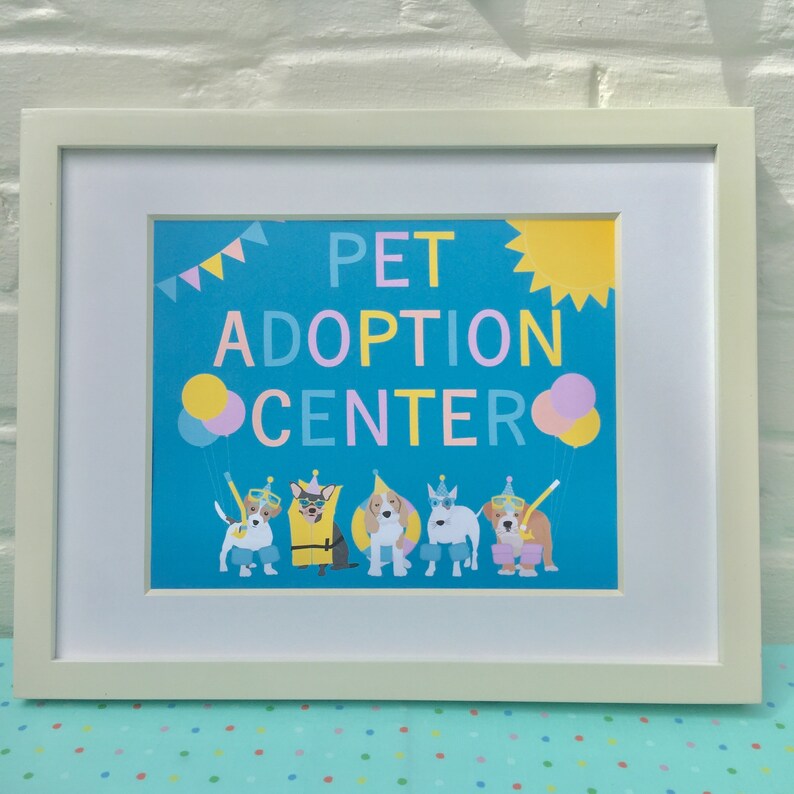 May include: A framed print with a blue background and the text "PET ADOPTION CENTER" in colorful letters. There are six cartoon dogs wearing party hats and sunglasses, and two balloons.