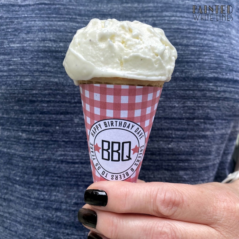 Pu&ograve; includere: Un cono gelato a quadretti rossi e bianchi con una pallina di gelato bianco in cima. Il cono ha un adesivo che dice "Buon compleanno Dave, Birre & BBQ per 55 anni, Salute!"