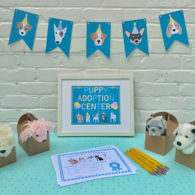 May include: A table set up for a puppy adoption event. There are stuffed puppies in boxes, a sign that says "Puppy Adoption Center", and a certificate of adoption form.