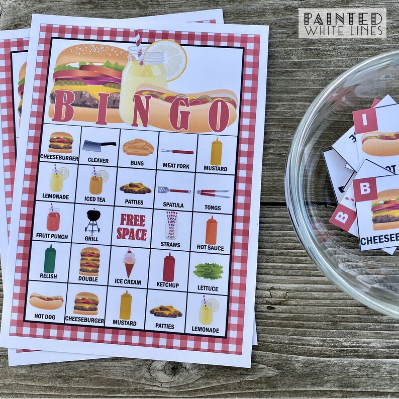 May include: A red and white checkered bingo card with a hamburger and hot dog design. The card has a free space in the middle and is filled with various food and grilling related items. The card is on a wooden table with a glass bowl of bingo chips.