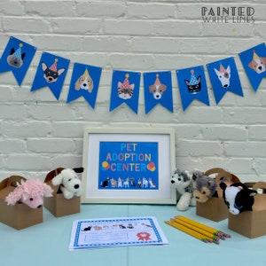 May include: A Pet Adoption Center party setup with a blue and white banner, a sign that says "Pet Adoption Center", and stuffed animal toys in brown boxes.
