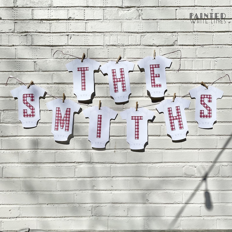 May include: A banner with the words "THE SMITHS" spelled out in white letters on red and white gingham fabric. The letters are attached to a string with clothespins.