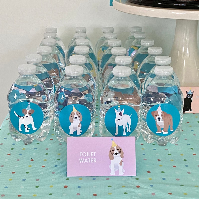 May include: A table covered in a blue and white polka dot tablecloth with clear plastic bottles decorated with dog illustrations and party hats. The bottles are labeled "Toilet Water".
