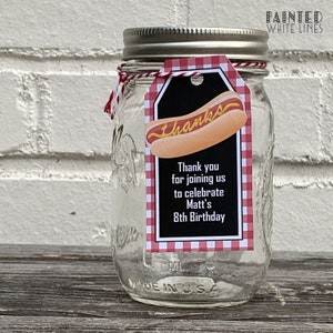 K&ouml;nnte beinhalten: Ein klares Glasgef&auml;&szlig; mit einem rot-wei&szlig; karierten Anh&auml;nger. Der Anh&auml;nger hat einen schwarzen Hintergrund mit dem Text "Danke" und einem Cartoon-Hotdog. Der Text auf dem Anh&auml;nger lautet "Vielen Dank, dass Sie mit uns gefeiert haben, um Matts 8. Geburtstag zu feiern".