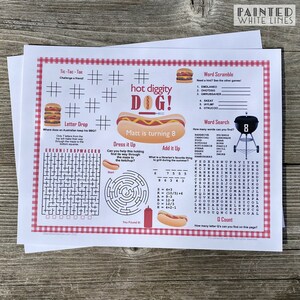 May include: A printable activity sheet with a hot dog theme. The sheet includes a word search, word scramble, tic-tac-toe, a maze, and a letter drop puzzle. The sheet is decorated with red and white checkered patterns and the text "hot diggity DOG!"