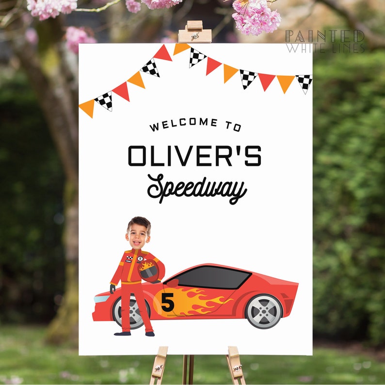 May include: A white sign with a red race car and a boy in a racing suit. The sign says "Welcome to Oliver's Speedway".
