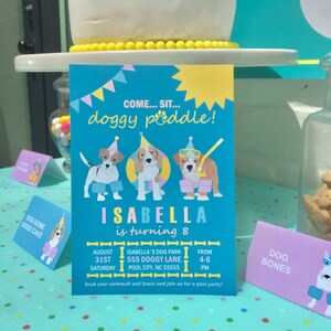 Puede incluir: Una invitaci&oacute;n de fiesta de cumplea&ntilde;os azul y amarilla con un perro de dibujos animados que lleva un gorro de fiesta y gafas de nataci&oacute;n. La invitaci&oacute;n dice "Come... Sit... Doggy Paddle!" e "Isabella cumple 8 a&ntilde;os". La invitaci&oacute;n tambi&eacute;n incluye la fecha, la hora y el lugar de la fiesta.