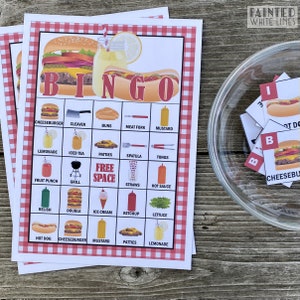 May include: A red and white checkered bingo card with a variety of food and drink items related to a barbecue or picnic. The card has the words "BINGO" at the top and "FREE SPACE" in the center. The items on the card include: cheeseburger, cleaver, buns, meat fork, mustard, lemonade, iced tea, patties, spatula, tongs, fruit punch, grill, straws, hot sauce, relish, double, ice cream, ketchup, lettuce, hot dog, cheeseburger, mustard, patties, and lemonade.