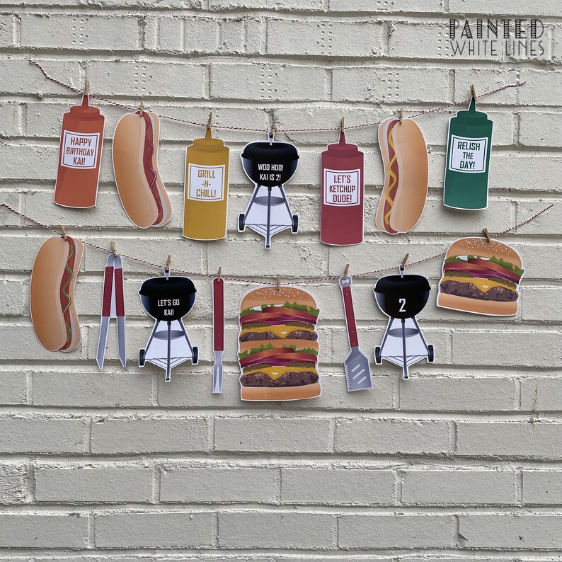 May include: A red, white, and blue birthday banner with a barbecue theme. The banner includes images of hot dogs, hamburgers, grills, ketchup, mustard, and relish. The banner also includes the text "Happy Birthday Kai", "Grill 'n Chill", "Moo Hoodi Kai 21", "Let's Ketchup Dude", "Relish the Day", "Let's Go Kai", and "2".