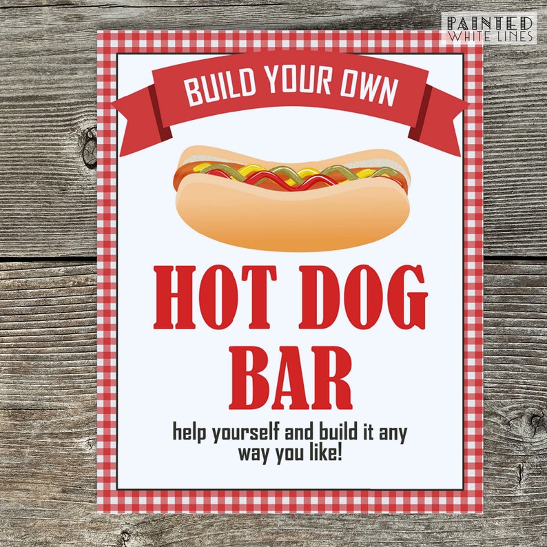 May include: A white sign with red and white checkered border, a red banner with the text "BUILD YOUR OWN" and a cartoon hot dog. The text "HOT DOG BAR" is in red letters. The sign says "help yourself and build it any way you like!"