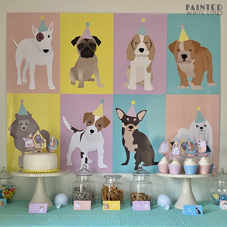 May include: A party scene featuring a backdrop with illustrated dogs wearing party hats. A cake and cupcakes are decorated with dog-themed toppers. Jars of treats and candies are arranged on a table with a light blue tablecloth. The text "PAINTED WHITE LINES" is visible.